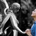 Mujer en oración frente a una estatua de ángel, simbolizando la conexión espiritual con el Arcángel Uriel para atraer abundancia y prosperidad.