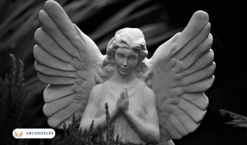 Estatua de un arcángel con alas extendidas y manos en posición de oración, representando paz y espiritualidad