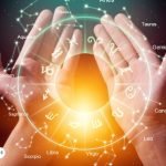 Representación de los signos zodiacales en un círculo de luz sobre dos manos, simbolizando la conexión espiritual entre los arcángeles y el zodiaco.