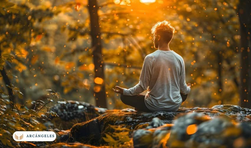 Persona meditando en un bosque iluminado por una luz dorada, representando la conexión espiritual con el arcángel Uriel y la energía de abundancia y claridad.