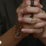 Manos rezando con un rosario en devoción al Arcángel Gabriel