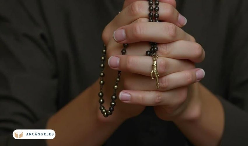 Manos rezando con un rosario en devoción al Arcángel Gabriel