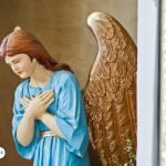 Estatua de San Gabriel Arcángel con alas doradas y vestimenta azul, en posición de oración, simbolizando guía y protección espiritual.