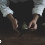 Persona sosteniendo una billetera con un billete en su interior, simbolizando la búsqueda de abundancia financiera y la conexión con el arcángel Uriel.